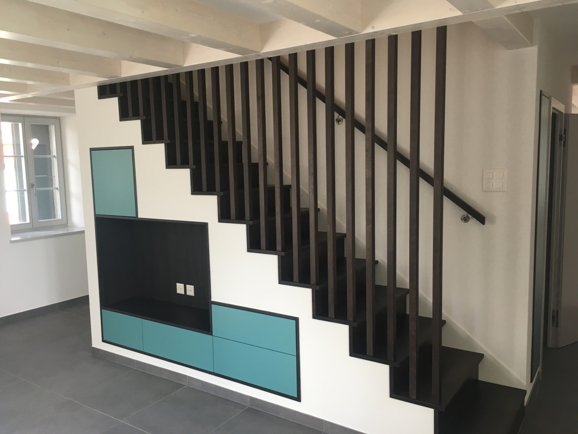 Escalier noir à claire-voie avec meuble intégré et façades turquoise