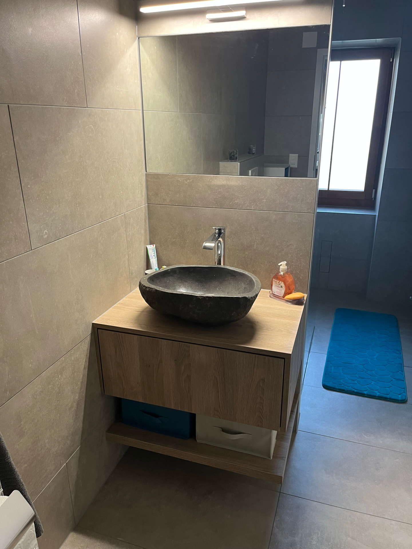 Vasque en pierre naturelle sur meuble suspendu en bois, miroir et applique LED