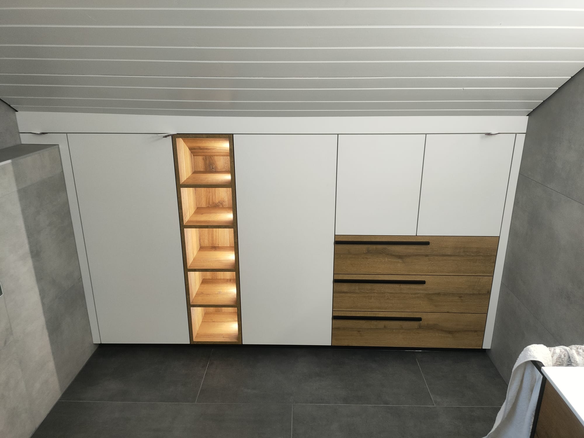 Rangements sur mesure blancs et bois clair avec niche verticale éclairée